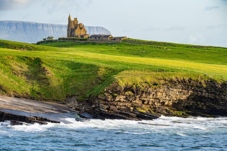 Ein historisches Schloss auf grünen Klippen am Meer entlang des Wild Atlantic Way.