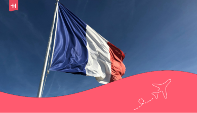 Die französische Flagge weht im Wind vor blauem Himmel. Passend zum Thema: Wofür ist Frankreich bekannt?