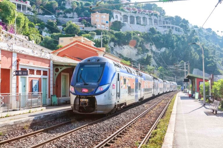 Ein blau-silberner SNCF-Zug fährt in einen Bahnhof an der Côte d’Azur ein.
