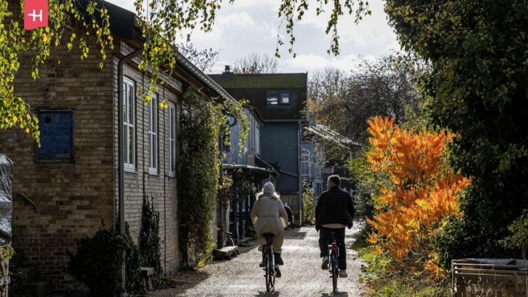 Ein Paar fährt mit dem Fahrrad durch eine idyllische Gasse in der Freistadt Christiania in Kopenhagen
