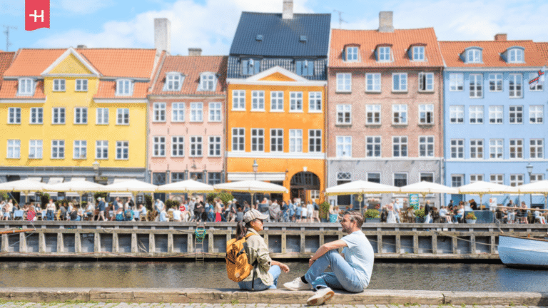 Zwei Personen sitzen am Pier des Hafenkanals Nyhavn in Kopenhagen.
