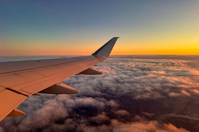 Blick aus dem Flugzeugfenster auf den Tragflügel bei Sonnenuntergang.