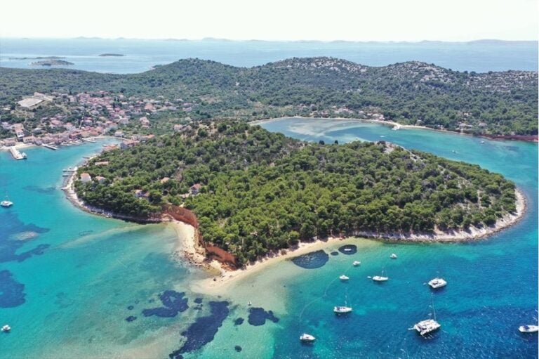 Luftaufnahme einer bewaldeten griechischen Insel mit einer Bucht.