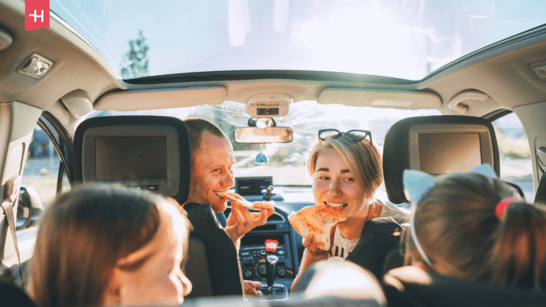 Eine Familie isst während der Autofahrt Pizza.