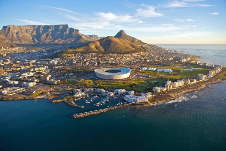 Eine Luftaufnahme von Kapstadt mit dem Tafelberg, dem Signal Hill und dem Kapstadt-Stadion an der Küste.