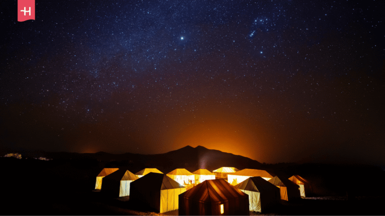 Erleuchtetes Wüstencamp in Marokko unter einem Sternenhimmel.