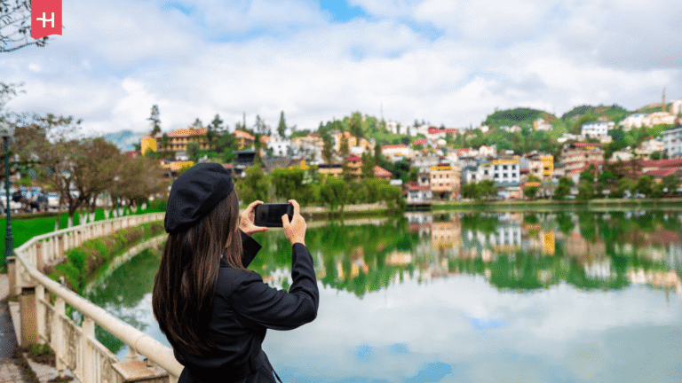 Eine junge Frau fotografiert mit ihrem Smartphone den Sapa-See in Vietnam.