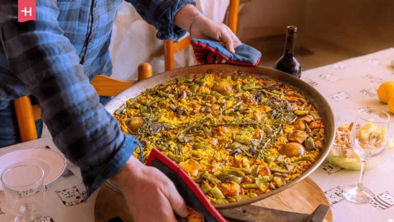Traditionelle Paella-Pfanne auf einem gedeckten Esstisch. 