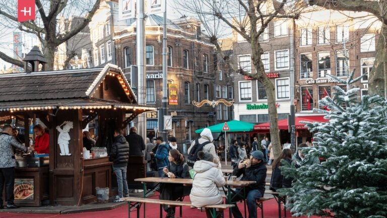 Ein städtischer Platz im Winter mit einem weihnachtlich beleuchteten Holzstand. 