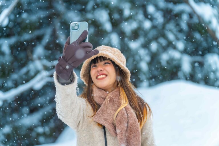 Eine lächelnde junge Frau macht bei dichtem Schneetreiben ein Selfie.
