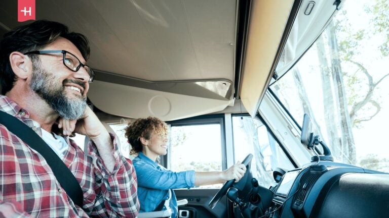 Ein lächelndes Paar unternimmt einen Roadtrip in einem Wohnmobil.