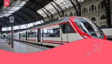 Rot-weißer Zug steht in einer Bahnhofshalle.