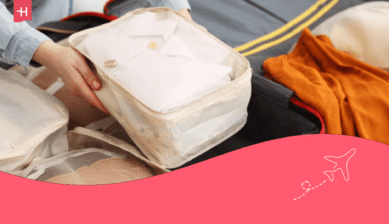 Eine Frau packt ihre Kleidung mithilfe von Packing Cubes in einen Koffer.