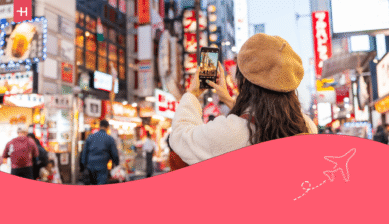 Frau fotografiert mit ihrem Smartphone eine belebte Straße in Japan.