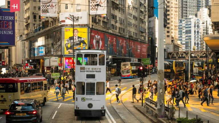 Straßenbahn und Passanten auf einer Kreuzung in Hongkong