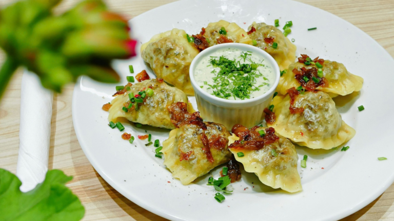 Ein Teller, auf dem Pierogi ansprechend angerichtet sind.
