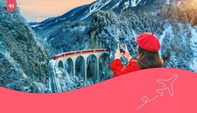 Frau fotografiert den Glacier Express auf einem Viadukt