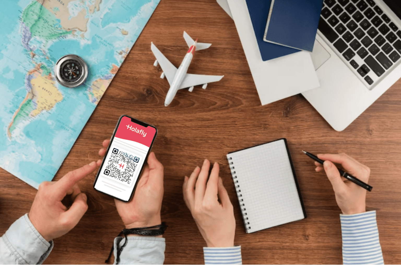 Profesionales organizando un viaje de negocios con un mapa, un portátil y un teléfono móvil, imagen que ilustra el uso de eSIM para empresas.