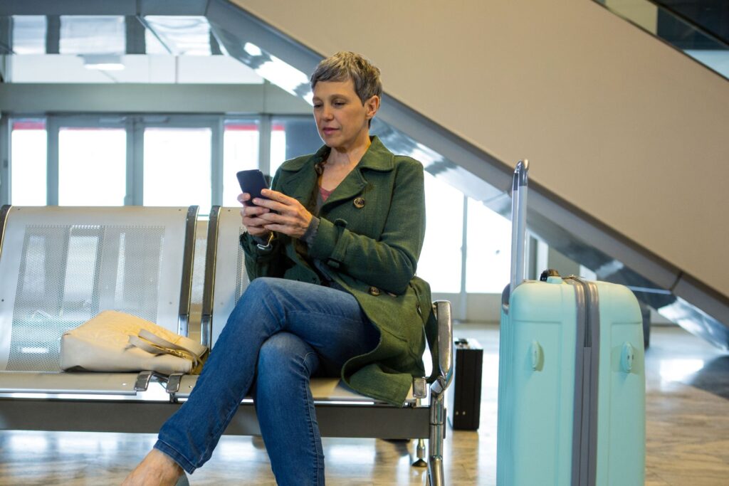 Una mujer revisando su teléfono móvil en un aeropuerto antes de viajar