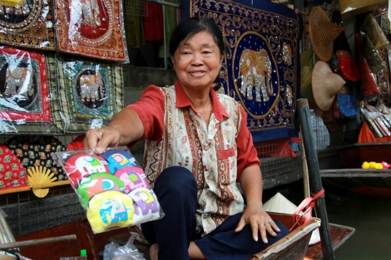 Mujer tailandesa vendiendo artesanías en un mercado flotante.