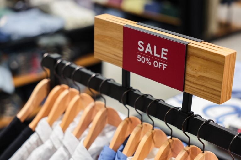Perchero de ropa con letrero de "SALE 50% OFF" en una tienda de ropa en NY.