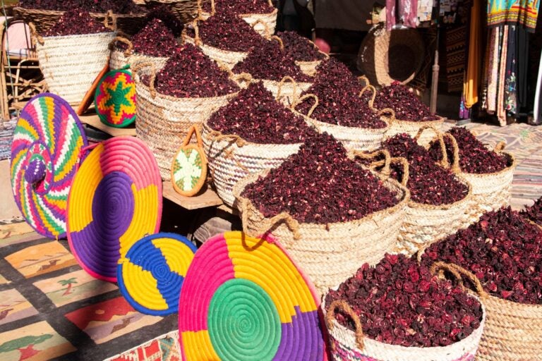Montones de hibisco seco en canastas de mimbre, exhibidos en un mercado tradicional egipcio.