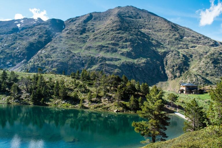 Paisaje del lago de les Truites en el parque natural del Comapedrosa, con lago, bosque y montañas.