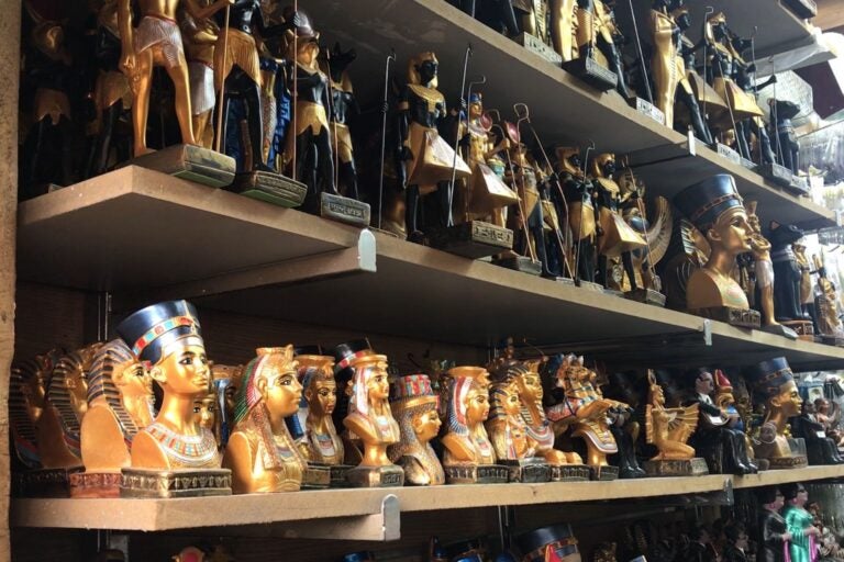  Estantería llena de estatuillas egipcias antiguas doradas y negras.