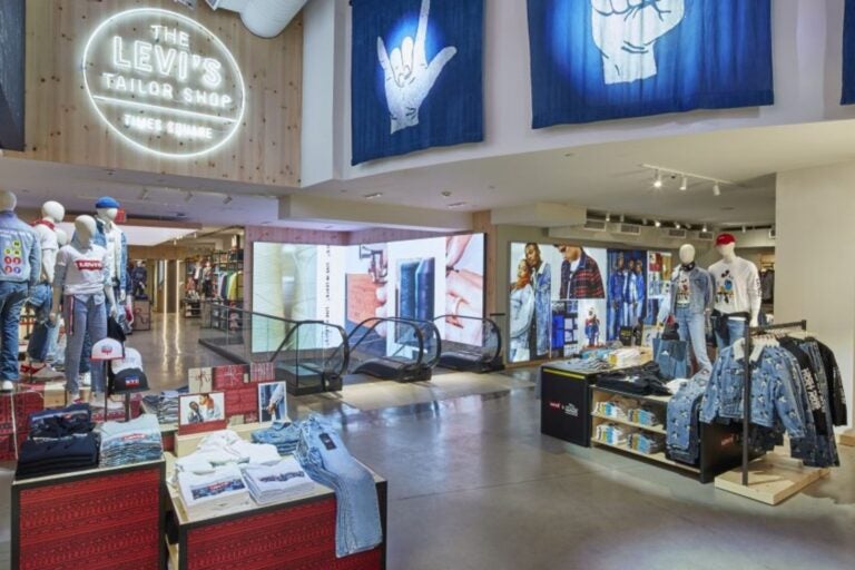 Interior de la tienda Levi's Tailor Shop en Times Square, con ropa en exhibición y letrero luminoso.