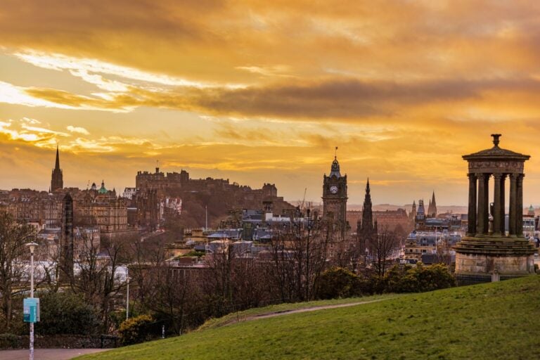 Monumentos en Calton Hill con Edimburgo al fondo durante el atardecer.