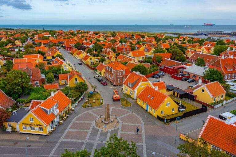Vista panorámica de Skagen, Dinamarca, con casas amarillas de tejas rojas y el mar al fondo.