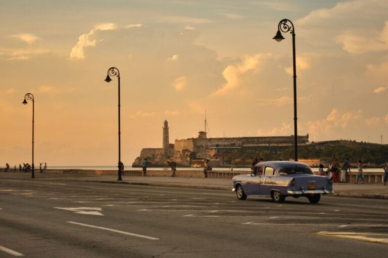 auto clasico azul recorriendo las calles de cuba en un atardecer