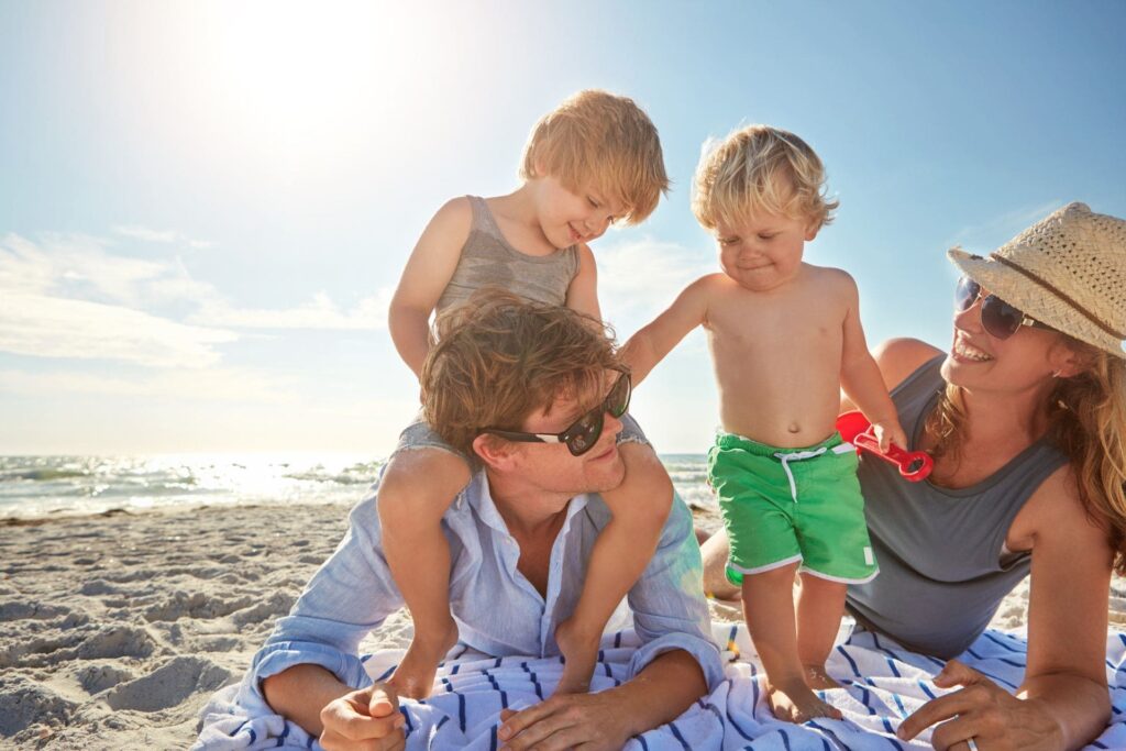 Padres con hijos en la playa, disfrutando del sol y el mar en Colombia.
