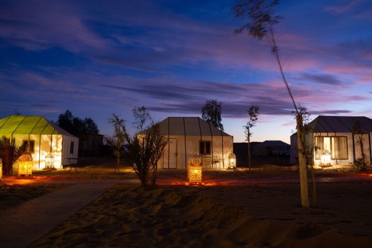 Haimas tradicionales iluminadas al anochecer en Akabar Luxury Desert Camp