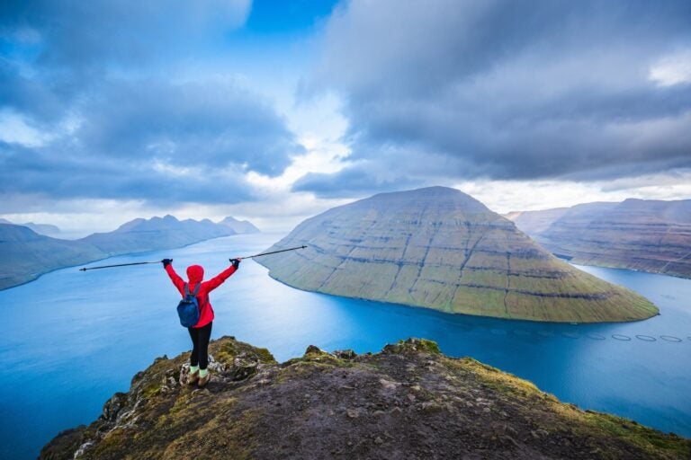 Senderista en la cima de una montaña en Kalsoy, Islas Feroe, con vistas espectaculares del paisaje.