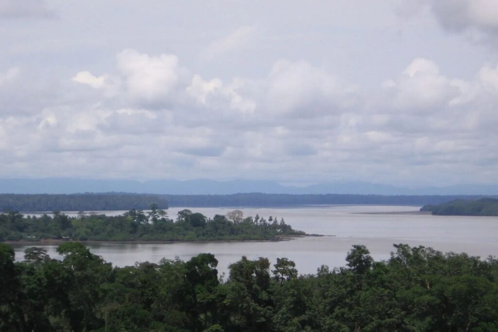 Vista del río Muni en Guinea Ecuatorial, mostrando su reserva natural con el ancho del río, islas boscosas, selva verde y cielo nublado.
