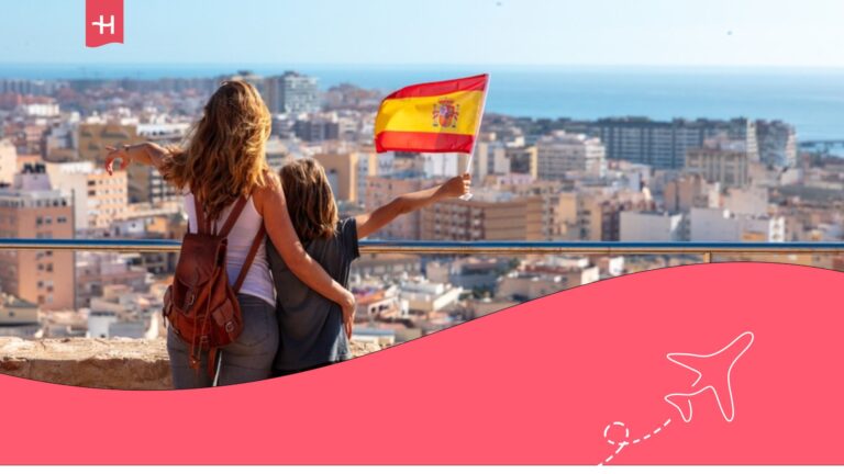 Mujer y niña con una bandera española en un mirador de una ciudad española.
