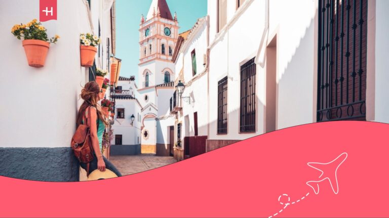 Mujer apoyada en una calle de edificios blancos de Málaga.