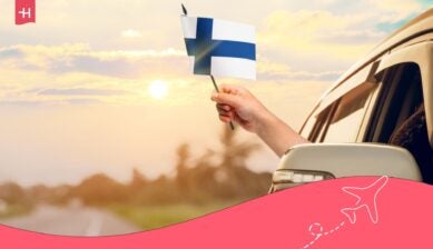 Persona conduciendo en coche y con una bandera de Finlandia.
