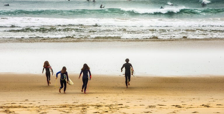 Familia de surfistas en playa de Lisboa