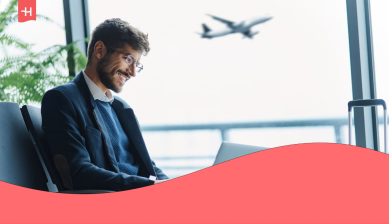 Profesional trabajando con su portátil en un aeropuerto, en el contexto de los beneficios globales para empleados que viajan por negocios.