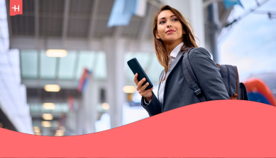 Mujer de negocios con mochila y teléfono móvil en un aeropuerto, imagen que ilustra consejos para viajes de negocios.