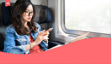 Mujer utilizando su teléfono móvil durante un viaje en tren, con Holafly Business Center como solución para gestionar la conectividad empresarial.
