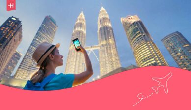 eune femme prenant une photo avec son smartphone des tours jumelles Petronas le soir à Kuala-Lumpur en Malaisie