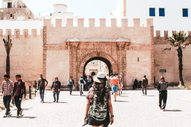 Jeune femme avec un sac à dos face aux portes de la médina de Essaouira