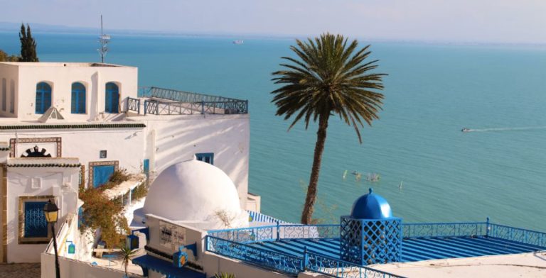 Une maison traditionnelle aux murs blancs en Tunisie, avec la mer en arrière-plan