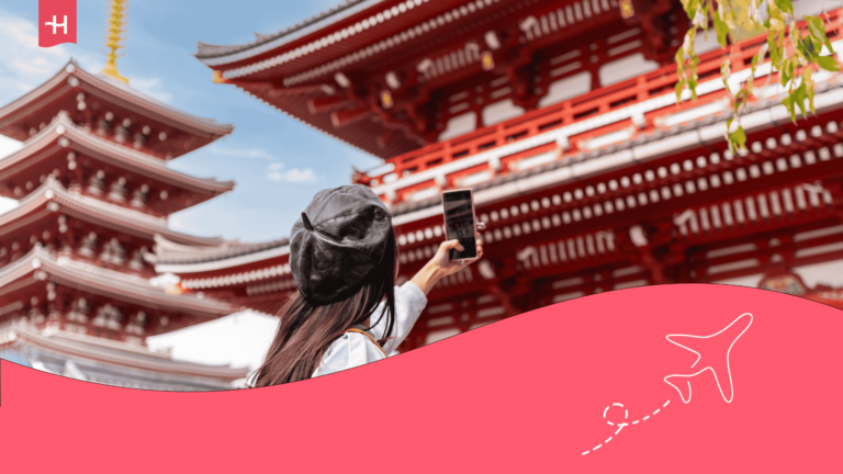 Voyageuse tenant son téléphone en l'air et prenant en photo un temple au Japon