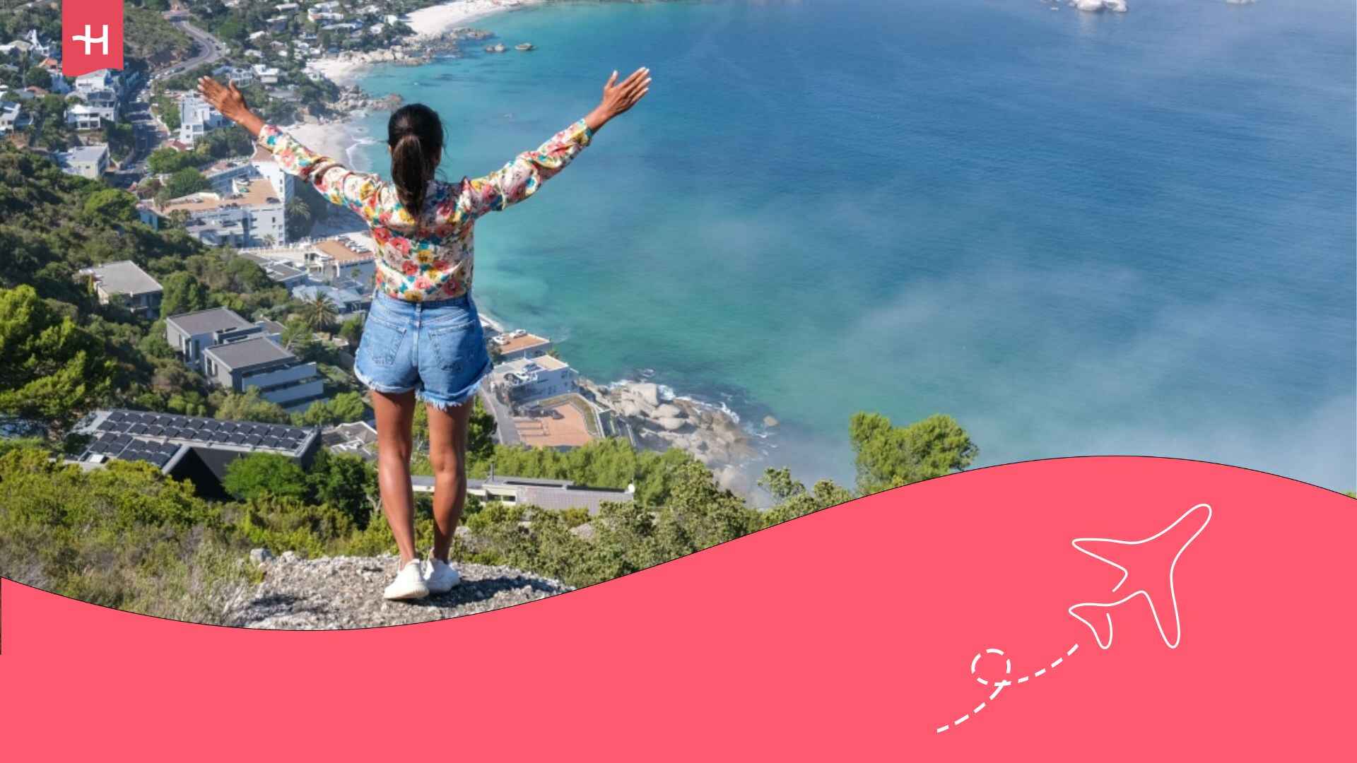 Une jeune femme avec les bras levés sur une falaise surplomba,t Campbay dans la ville du Cap en Afrique du Sud