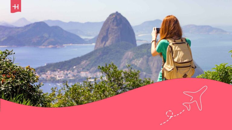 Une jeune femme avec un sac à dos prenant des photos en bord de mer au Brésil