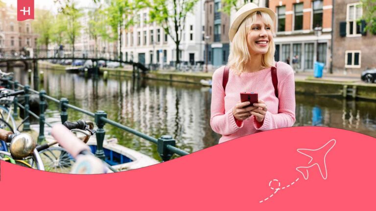 Voyageuse souriante sur le quai à Amsterdam utilisant son téléphone avec l'itinérance des données